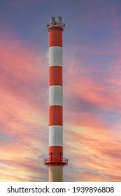 Tall Old Red And White Factory Smoke Stack Isolated Against A Colorful Sunset Sky