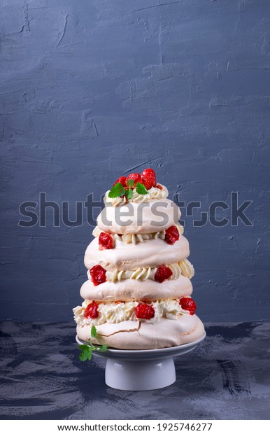 Tall Pavlova\
cake with whipped cream and strawberry against the gray background.\
Multilayered meringue\
dessert