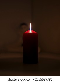 Tall Red Candle Lit In A Dark Room 