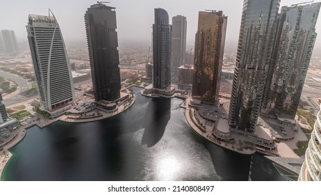 Tall residential buildings at JLT district aerial timelapse during all day, part of the Dubai multi commodities centre mixed-use district. Shadows moving fast. Hazy weather