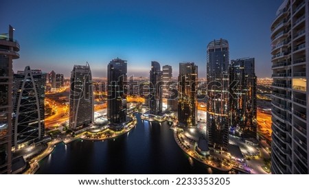 Tall residential buildings panorama at JLT district aerial night to day transition timelapse, part of the Dubai multi commodities centre mixed-use district. Illuminated towers and skyscrapers
