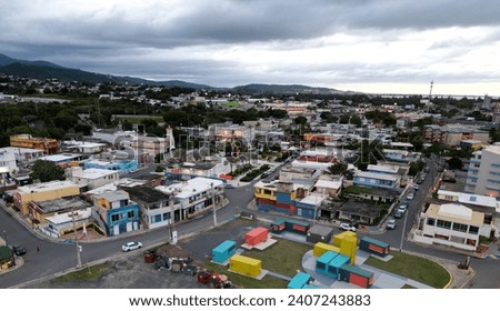 tall seaside residential buildings in Luquillo, Puerto Rico (aerial drone view) colorful colonial downtown with waves on beach, mountains (el yunque rainforest), shore, road with cars (sunset, dusk)