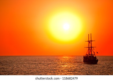 Tall Ship Drifting In The Open Sea At Sunset.