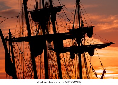 Tall Ship Masts And Rigging Silhouetted Against A Dramatic Sky At Sunset