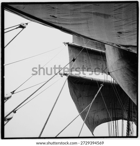 Tall ship with sails full of wind, from aboard, black and white sqaure film negative