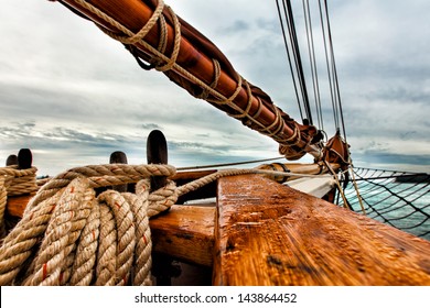 Tall ship schooner sailing on open water. Detailed close up of rigging, bow and boom and the textures of rope and wood.