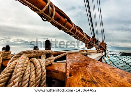 Tall ship schooner sailing on open water. Detailed close up of rigging, bow and boom and the textures of rope and wood.