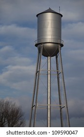 Tall Silver Water Tower With Cloudy Blue Sky Background