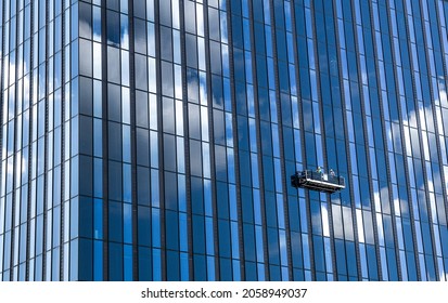 A Tall Skyscraper And Professional High Rise Window Cleaning Service Workers In A Gondola