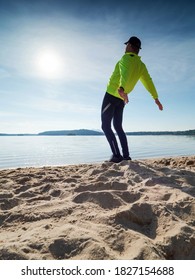 Tall Slim Man Doing Stretching On The Beach On A Sunny Morning.  Body Stretching Before Doing Sports.