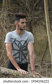 A Tall Slim Young Boy Relaxes In A Nature Park. The Boy Is Wearing Summer Clothes. The Young Man Enjoys Nature. 