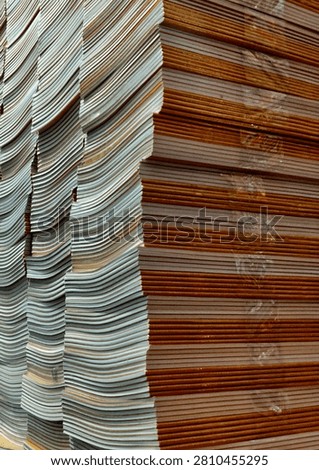 Tall stack of blank notebooks and books piled high at a book fair or stationery store. Bulk stock of school supplies, education, and learning concept with natural lighting