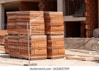 A tall stack of bricks packed on a pallet at a construction site. High strength building materials