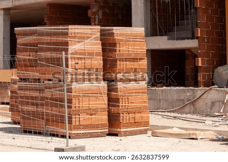 A tall stack of bricks packed on a pallet at a construction site. High strength building materials