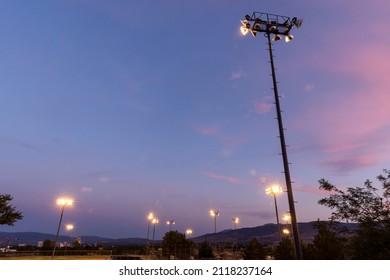 Tall Stadium Light Pole Over A Baseball Field At Sunset