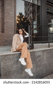  Tall stylish girl with oversized jacket posing near the railing and steps on the city background - Shutterstock ID 2142816055