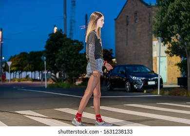 Tall Teenage Girl Crossing Street On Pedestrian Crossing In Auckland City At Night, New Zealand.