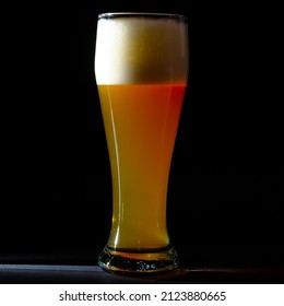 A Tall Transparent Glass Of Beer In A Narrow Beam Of Light On A Black Background.