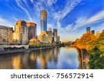 Tallest Melbourne skyscraper Eureka tower dominates South Yarra cityscape over Yarra river in warm morning sunlight under blue sky.