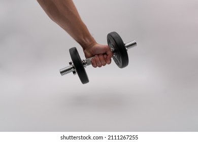 Tallinn, Estonia - 01.22.2022: Man Holding A Dumbbell. Only One Hand And A Dumbbell On The Image. White Background Image. Workout Session With Small Weights. Home Gym Equipment