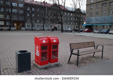 TALLINN, ESTONIA - APRIL 7, 2018: Bus Stop Is Equipped With Wooden Bench, Black Square Trash Bin And Two Vertical Metal Red Empty Newspaper Boxes With Front Glass, Each Box For Different Language.