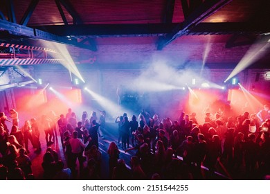 TALLINN, ESTONIA - Feb 13, 2022: A Group Of People Enjoying Their Time At A Party With Colorful Lights In A Warehouse