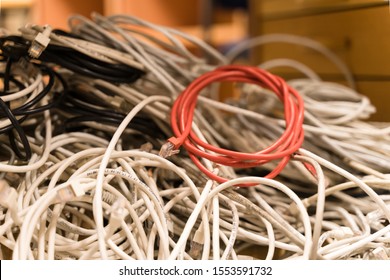 Tallinn / Estonia - November 07 2019:  Tangled Network Cables Gathered Into One Bunch During Clean Up. Liquidation Process Of The Business, Messy Cubicle Office. Red Rolled Wire Withing Grey Ones. 