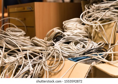 Tallinn / Estonia - November 07 2019:  Tangled Network Cables Gathered Into One Bunch During Clean Up. Liquidation Process Of The Business, Messy Cubicle Office. Blue Wire Withing Grey Ones In Box.