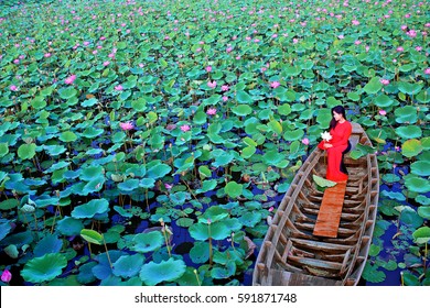 Tam Da lotus lake, Ho Chi Minh city, Vietnam - February27, 2017: Vietnamese woman wearing red traditional clothing (Ao dai) sitting on sampan in lotus lake