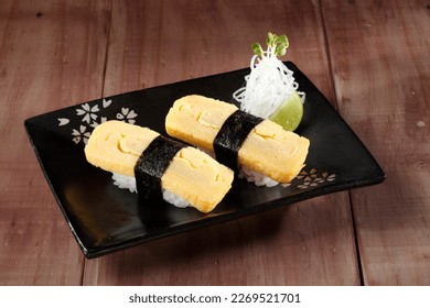  Tamago Sushi nigiri or Sweet egg sushi in black plate on wooden background.  - Powered by Shutterstock