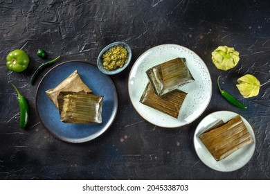 Tamal, traditional dish of Mexican cuisine, various stuffings wrapped in green leaves. Hispanic food. With chili peppers and tomatillos, top shot