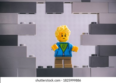 Tambov, Russian Federation - August 26, 2020 Lego Boy minifigure looking through a hole in gray wall.
