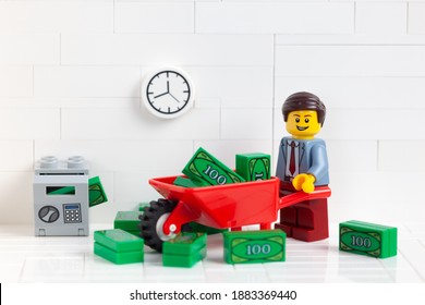 Tambov, Russian Federation - December 23, 2020 Lego businessperson minifigure transporting money in a wheelbarrow.