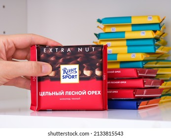 Tambov, Russian Federation - February 19, 2022 Woman Hand Taking Ritter Sport Hazelnut Chocolate Bar From Shelf Of Kitchen Cupboard