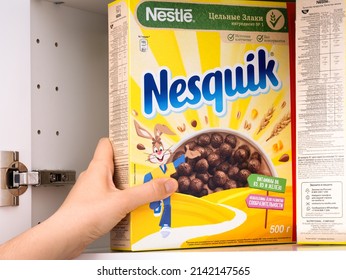 Tambov, Russian Federation - February 19, 2022 Woman Taking Nestle Chocolate Nesquik Cereal Box Out Of A Kitchen Cupboard