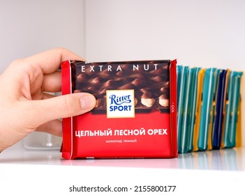 Tambov, Russian Federation - February 19, 2022 Woman Hand Taking Ritter Sport Hazelnut Chocolate Bar From Stack On Shelf Of A Kitchen Cupboard