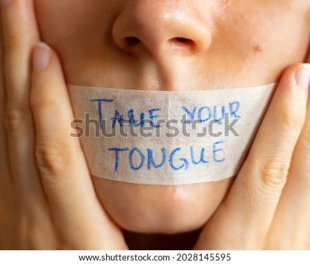 Tame your tongue handwritten Bible quote on plaster on woman's lips. Christian teaching power of mouth words. A closeup.