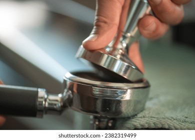 Tamped espresso finely ground coffee from coffee grinder grinds freshly roasted coffee beans with a tamper. Fine coffee pressed by tamper.