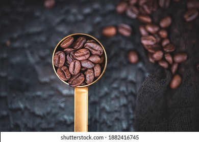 Tamped Puck Of Coffee Grounds Within Basket Of Portafilter And Coffee Beans Spilled Around In A Dark And Moody Scene Of Natural Light.