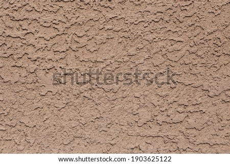A tan colored abstract stucco background.