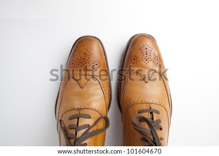 Tan fashionable male brogue shoes on white background view from above