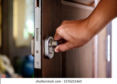 A tan hand twist the stainless steel locking knob to lock the wooden door
