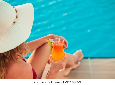 Tan Sexy Body Girl Near The Pool In Red Swimsuit In A Hat With A Cocktail. Relax And Having Fun On Vacation. Pool Party. Outdoor Lifestyle