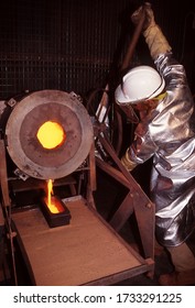 Tanami Desert, Northern Territory, Australia, May 20, 1995: View Of Gold Mine Worker Wearing Heat Protective Clothing And Mask Pours Molten Gold Into Ingot Mold