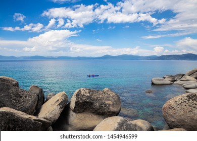 Tandem Kayak In The Middle Of Beautiful Blue Water Of Lake Tahoe With Boulders In The Foreground