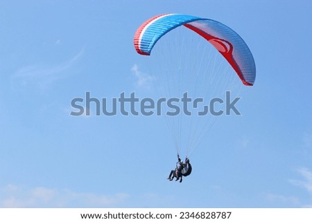 Tandem Paraglider flying in a blue sky