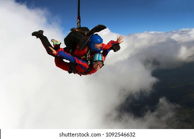 Tandem skydiving. Man and woman are flying near clouds.