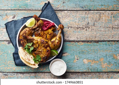 Tandoori Chicken Marinated In Tikka Served With Rice Naan, Lime, Plain Yoghurt And Cilantro. Indian Cuisine, Tikka Starter On Wooden Background With Copy Space