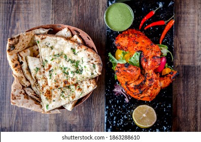 Tandoori Chicken on Black Platter with Naan on Sides