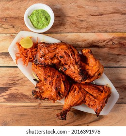 Tandoori chicken - prepared by roasting chicken marinated in yoghurt and spices in a tandoor, served over a wooden rustic background. selective focus